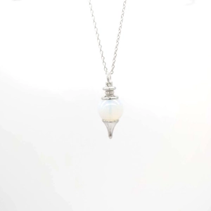 Detailed macro view of white opal gemstone pendant with silver sword flower filigree