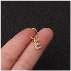 Boucle d'oreille pendentif lettre E dorée avec zircons brillants portée au cartilage