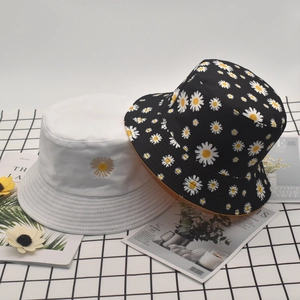 Detail view of cotton daisy bucket hats in white and black floral reversible patterns