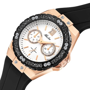 Macro detail of rose gold watch bezel with sparkling crystals and black rubber strap