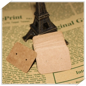 Close-up of blank kraft paper earring cards with two holes on vintage newspaper background