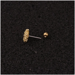 Golden flower cartilage earring with clear zircon crystals on black textured background