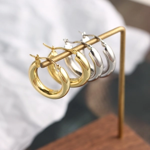 Polished 18K gold and silver hoop earrings on a T-bar stand in a minimalist style
