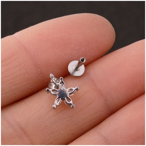 Polished stainless steel star labret stud with zircon and screw flat back on fingertip
