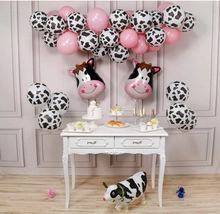 Detail of cow-themed balloon arch with pink accents and cow head foil balloons