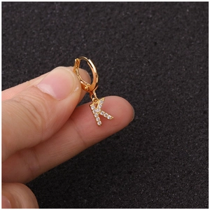 Boucle d'oreille lettre K dorée avec pierres en zircon tenue entre les doigts