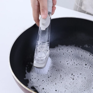 Hydraulic kitchen dish brush with long handle cleaning a black pot with rich foam