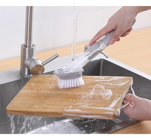 Detail of soap dispensing kitchen brush cleaning a wooden cutting board with thick foam