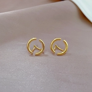 Detail of round geometric hollow earrings in gold finish on soft satin background