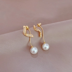 Macro view of gold tassel earrings featuring rectangular zircons and white pearls