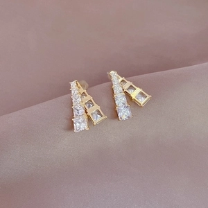 Detailed close-up of golden geometric earrings with double-row clear cubic zirconia