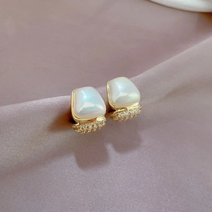 Macro shot of gold geometric earrings with iridescent white stones and cubic zirconia details