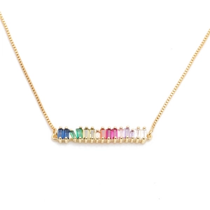 Close-up of golden copper necklace featuring a horizontal bar with colorful zircon stones