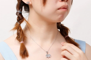 Close-up of a model wearing the silver elephant pendant necklace and stud earring set