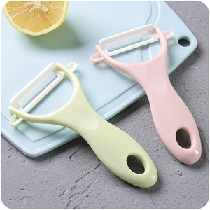 Ceramic fruit peeler set in pink and green on blue cutting board with lemon slices