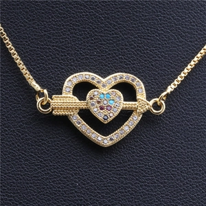 Gros plan du pendentif cœur doré avec zircons colorés et flèche sur cuir noir texturé