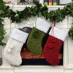 Trois chaussettes de Noël en tricot rouge, vert et blanc suspendues à une cheminée décorée