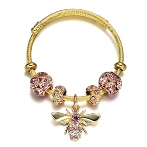 Detailed close-up of golden bee charm and pink crystal beads on twisted bangle bracelet