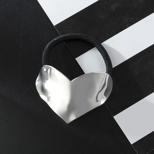 Minimalist metallic heart hair tie with textured silver finish on striped background