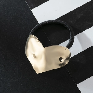 Modern black elastic hair tie featuring a large textured gold heart metal ornament