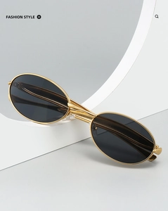 Détail de lunettes de soleil ovales en métal avec monture dorée et verres teintés sombres