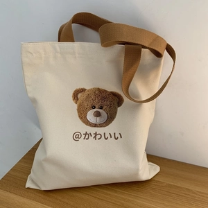 Detail of canvas tote bag with brown bear embroidery and wide woven handles