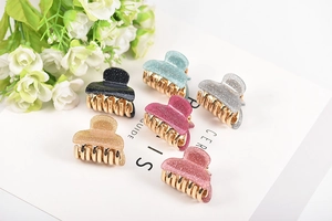 Glitter acrylic hair claws in six colors with gold metal teeth on a white card