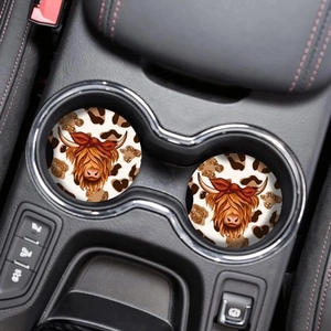 Close-up of dual round highland cow car coasters with leopard print in a vehicle cup holder