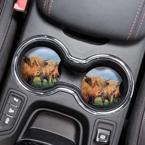 Close-up of two highland cow car coasters made of absorbent wood in a vehicle cup holder