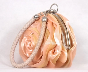 Detail view of peach silk rose evening bag with silver metal clasp and woven handle