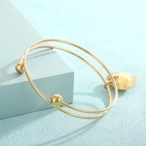 Detailed close-up of double-layer gold stainless steel bracelet with heart pendant charm