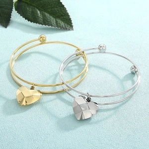 Detail of double-layer stainless steel bracelets with geometric heart pendants in gold and silver