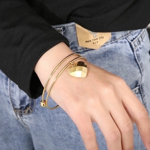 Macro shot of double-layer gold stainless steel bracelet with geometric heart charm