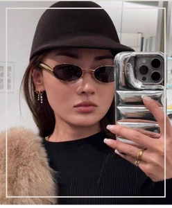 Détail de lunettes de soleil ovales en métal doré avec un chapeau équestre noir