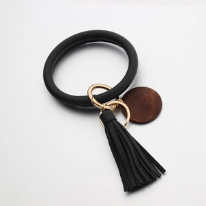 Detail van zwarte lederen armband-sleutelhanger met franje en houten hanger-bedeltje
