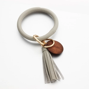 Beige leather bracelet keychain with wooden disc pendant and fringe tassel detail