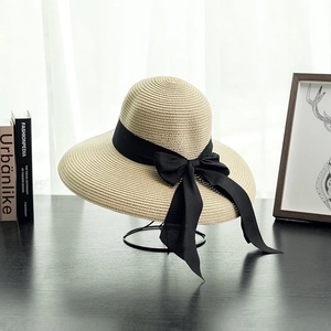 Elegant beige straw sun hat with black ribbon bow, French retro style for beach vacations