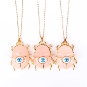 Pink crystal beetle pendant necklace with blue eye detail on a gold chain for women