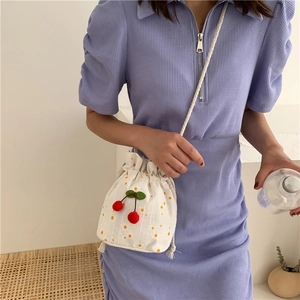 Detail of white canvas bucket bag with 3D cherry decor and yellow polka dot patterns