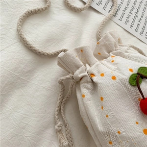 Detail of white canvas bucket bag with orange floral print and 3D cherry decoration