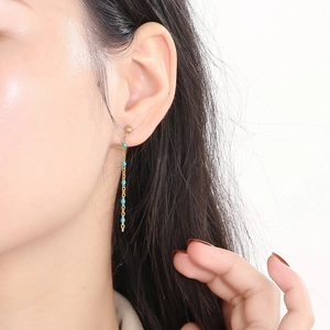 Bohemian gold chain tassel earrings with turquoise beads worn on a female model