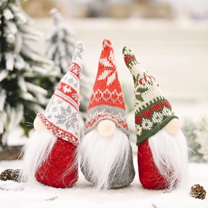 Drie kerstkabouters met gebreide mutsen en baarden van nepbont op witte sneeuw