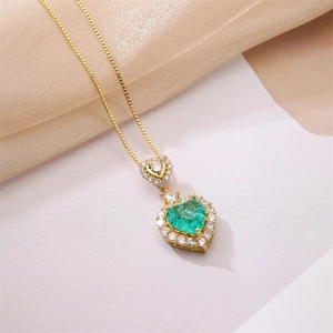 Close-up of gold necklace with emerald heart pendant and micro-pave diamond halo