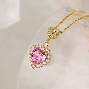 Close-up of gold necklace with double heart pink gemstone pendant and zircon accents