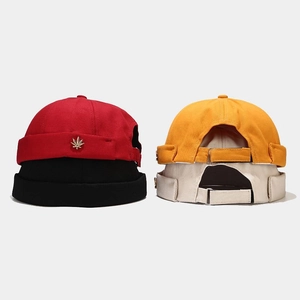 Detailed view of brimless docker hats in four colors with gold maple leaf metal badges