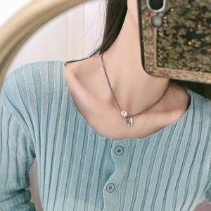 Close-up of vintage silver necklace with square pendant and small bead on a model