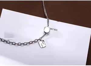 Close-up of vintage silver necklace with Good Luck square pendant and round links