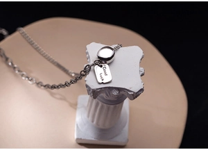 Macro shot of vintage silver square tag necklace with Good Luck engraving on mini pillar