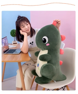 Detail of soft green dinosaur plush toy featuring a lollipop embroidery on the belly