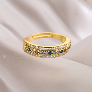 Macro detail of gold adjustable ring with multicolored zircon stones on white satin